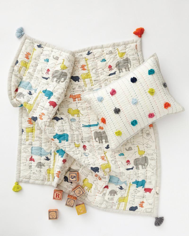 Pehr Multi Noah's Ark Blanket with Pehr Pom Pom Multi Decor Pillow and ABC blocks. Screen printed, cotton. White with animal print, reverse side plain white, coloured tassels on the corners.