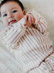 Pehr Long Sleeve Romper. Certified organic cotton. White with pink stripes, shown on baby.